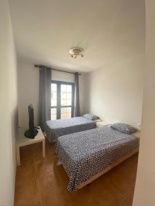 a room with two beds and a television in it at Long Beach Surf House in Corralejo