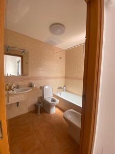 ein Badezimmer mit einem WC, einer Badewanne und einem Waschbecken in der Unterkunft Long Beach Surf House in Corralejo