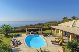 a swimming pool with chairs and a house at Villa Hephaestus Spartia Kefalonia in Spartia