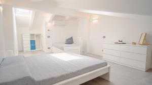 a white bedroom with a bed and a chair at Elide Home Sweet Home - Italian Homing in Padenghe sul Garda
