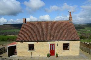 una pequeña casa de ladrillo con puerta roja en Threp'nybit Cottage, en Carlton