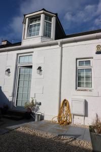 a white building with a window on the side of it at Beachcomber Cottage in Troon