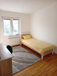 a bedroom with a bed and a rug and two windows at Itaka - Belgrade City Center in Belgrade
