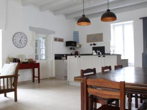 een keuken en eetkamer met een tafel en een klok bij Maison Saint-Georges-d'Oléron, 10 pièces, 15 personnes - FR-1-246A-61 in Saint-Georges-dʼOléron