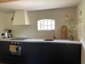 eine Küche mit schwarzen Schränken, einem Waschbecken und einem Fenster in der Unterkunft Rönnebröd in Rönnebröd