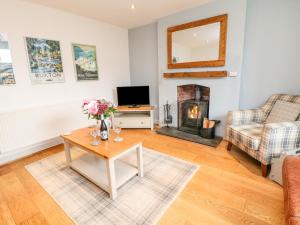 a living room with a table and a fireplace at Bank Cottage in Buxton