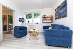uma sala de estar com duas cadeiras azuis e uma mesa em Ferienwohnung Sonnenriff em Bensersiel