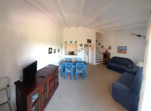 ein Wohnzimmer mit einem Sofa und einem Tisch mit blauen Stühlen in der Unterkunft Le case di Stella Maris in Palau