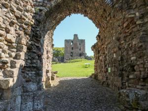 an archway in a castle with a ruin in the background at 8 Pedwell Way in Berwick-Upon-Tweed