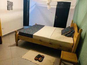 a small bed in a room with shoes on the floor at Tea House BNB in Kigali