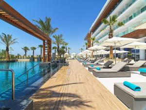 a row of lounge chairs next to a pool at a hotel at Amanti, MadeForTwo Hotels - Ayia Napa in Ayia Napa