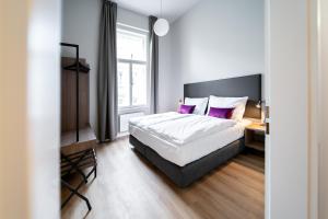 1 dormitorio con 1 cama grande con almohadas moradas en Karl BY ZEITRAUM, en Praga