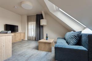 a living room with a blue couch and a tv at Hotel & Restaurant Rödersaal in Großröhrsdorf