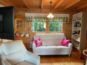 sala de estar con sofá blanco y almohadas rosas en Koivuranta en Ähtäri