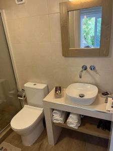 uma casa de banho com um WC, um lavatório e um espelho. em OASIS rooms em Caristo