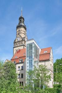 un edificio alto con una torre de reloj encima en Philippus Inklusionshotel Leipzig, en Leipzig