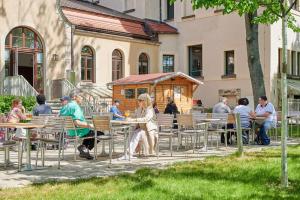 um grupo de pessoas sentadas em mesas fora de um edifício em Philippus Inklusionshotel Leipzig em Leipzig