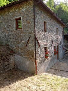 a stone building with two windows and flowers on it at Mulini di Verrucole in Naggio