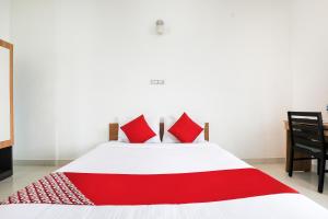 a bedroom with a white bed with red pillows at Flagship 82361 Black Pearl Residency in Pīlamedu