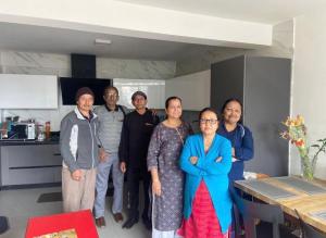 a group of people posing for a picture in a kitchen at Norbu Thungkar Homestay in Darjeeling