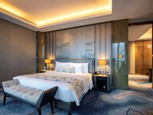 a bedroom with a large bed and a chair at Pullman Yantai Center in Yantai