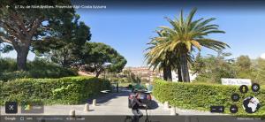a person with a backpack walking down a sidewalk at Antibes Secured Parc Velusine with private parking, Terrace, Pools and Tennis courts. in Antibes