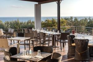 a restaurant with tables and chairs with the ocean in the background at Porto Belissario in Ferma