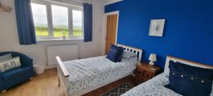 een slaapkamer met 2 bedden en een blauwe muur bij Merrifield House Devon in Kingsbridge