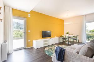 un soggiorno con divano, TV e tavolo di Appartamenti Villa al Fiume a Torbole