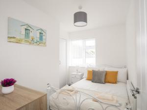 a white bedroom with a white bed with yellow pillows at Valley House in Holyhead