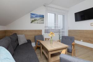 a living room with a couch and a table at Willa Szamotulanka - Pokoje Wakacyjne Rewal - Plac Zabaw & Grill - by Noclegi Renters in Rewal