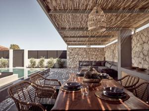 a patio with a wooden table and chairs at Noema Villa in Zakynthos