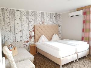ein Schlafzimmer mit einem großen weißen Bett und einem Stuhl in der Unterkunft Hotel Schachner in Maria Taferl