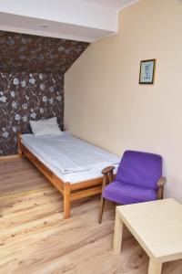 um quarto com uma cama e uma cadeira roxa em Gospodarstwo Agroturystyczne & SPA z Alpakami em Ełk