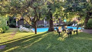 a group of chairs sitting under a tree near a pool at Casa da Roseira in Ponte de Lima
