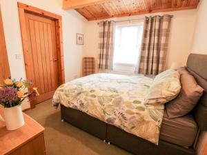 um pequeno quarto com uma cama e uma janela em The Log Cabin em Tenbury
