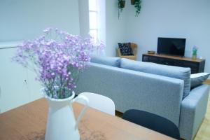 uma sala de estar com um sofá azul e uma mesa com flores roxas em Pretty town hall apartment em Tarragona