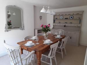 a dining room with a wooden table and white chairs at Creel Cottage in Cullen