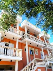 un edificio naranja con balcones blancos y árboles en Marku Palace, en Ksamil