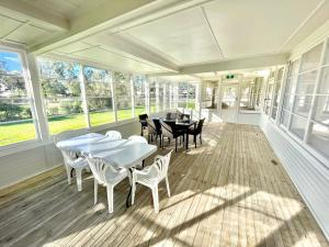 a screened porch with tables and chairs and windows at The Pink House in Walgett
