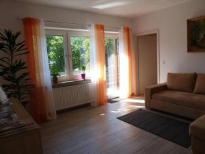 a living room with a couch and two windows at Ferienwohnung zur Altmühl in Pappenheim