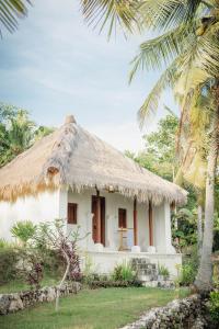 a small white house with a thatched roof at Umah Ilu Island Retreat Penida in Toyapakeh