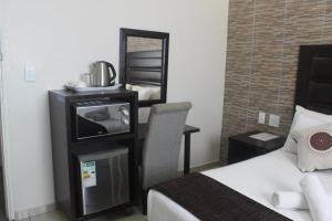 a hotel room with a bed and a tv and a mirror at Bayside Lodge Empangeni in Empangeni