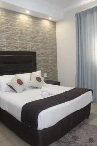 a bedroom with a large bed with white sheets and pillows at Bayside Hotel Empangeni in Empangeni