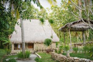 a house with a thatched roof in a garden at Umah Ilu Island Retreat Penida in Toyapakeh