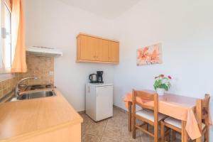 a small kitchen with a sink and a table with chairs at Aleka Apartment 1 in Agios Georgios