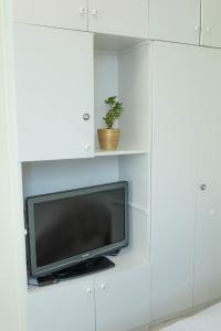 a tv in a white cabinet with a potted plant at HAPPY in Zagreb