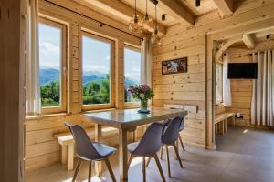 a dining room with a table and chairs and windows at Peak House dom wakacyjny z widokiem na Tatry i Giewont in Kościelisko
