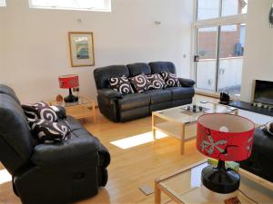 a living room with a black leather couch and a table at Annapurna in Portpatrick