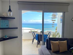 een woonkamer met een tafel en uitzicht op de oceaan bij Departamentos Amoblados Frente al Mar Manta -PROINKASA in Manta